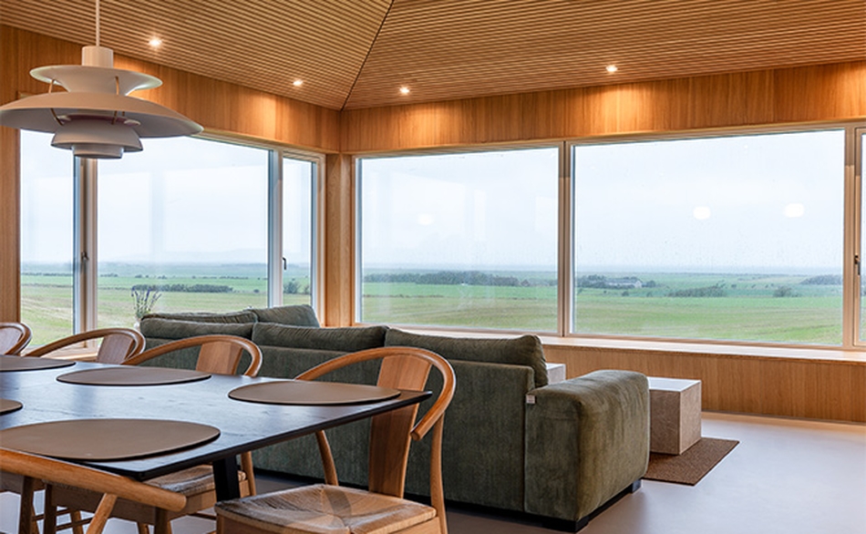 Sommerhus i Lemvig med træloft fra I-Wood Denmark® og udsigt gennem store vinduespartier.